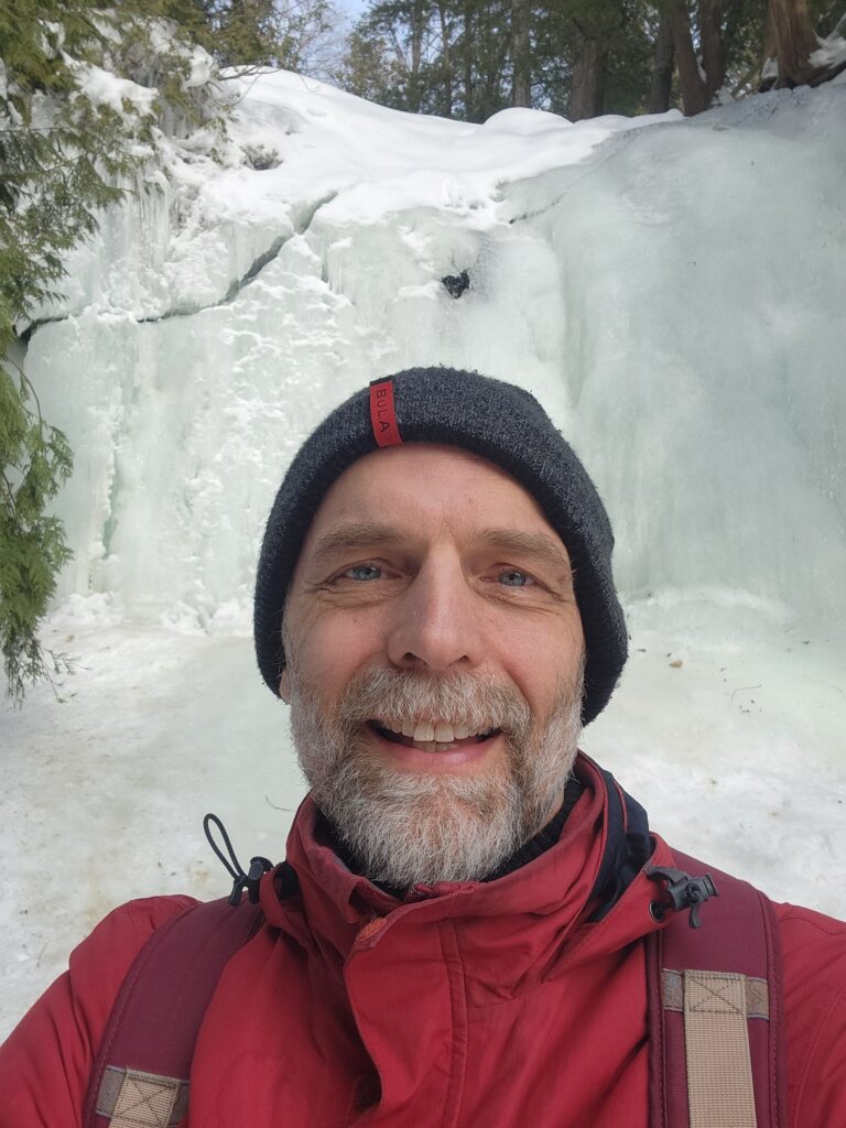 Charles de Bueger in front of a frozen waterfall